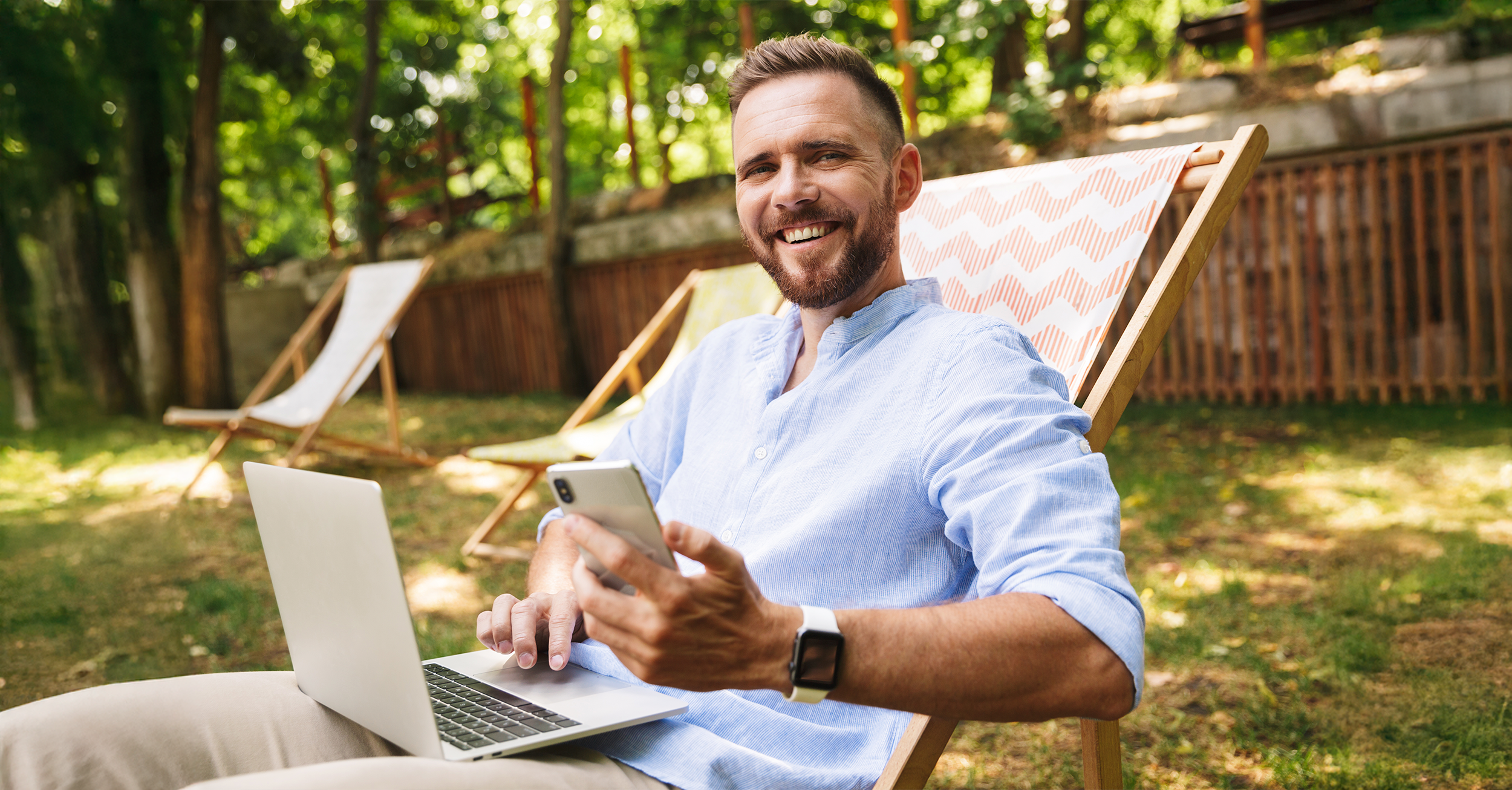 photo - Happy man on lawn chair with phone and laptop 